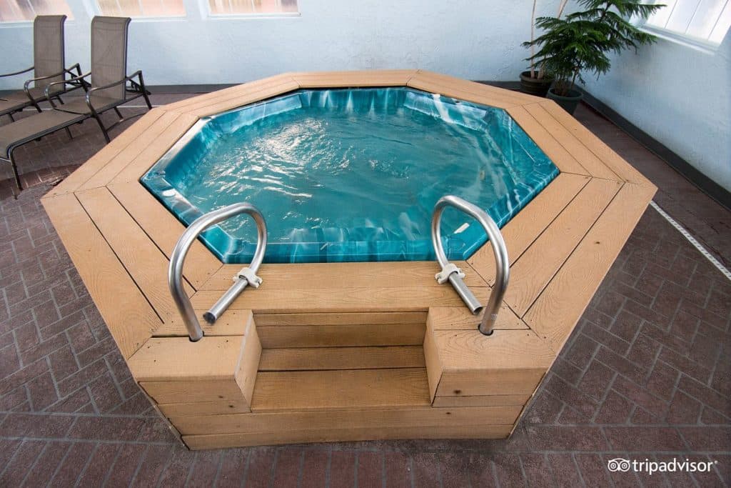 Indoor hot tub spa area at Angel Inn Central in Branson, Missouri, featuring an octagonal soaking pool with handrails and lounge seating