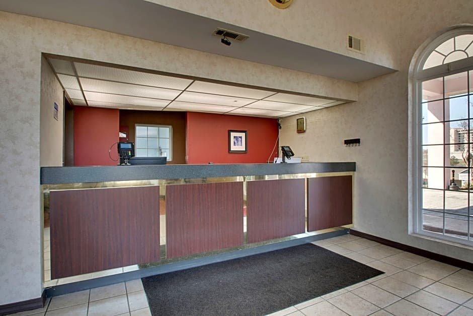 Front desk and lobby area at Angel Inn Central in Branson, Missouri with a reception counter, tiled flooring, and a large arched window