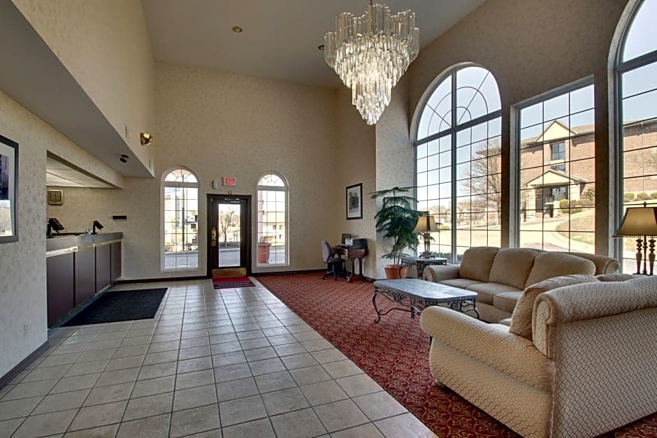 Spacious hotel lobby at Angel Inn Central in Branson MO with a chandelier, arched windows, front desk area, and comfortable seating