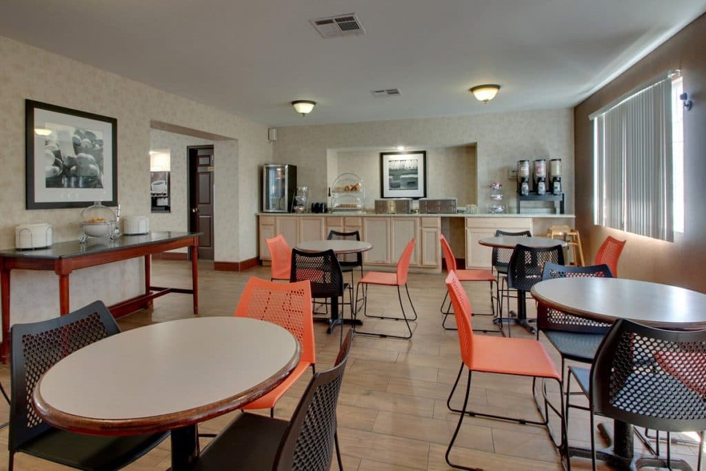 Angel Inn Central breakfast area in Branson MO with round tables, orange and black chairs, and a buffet counter
