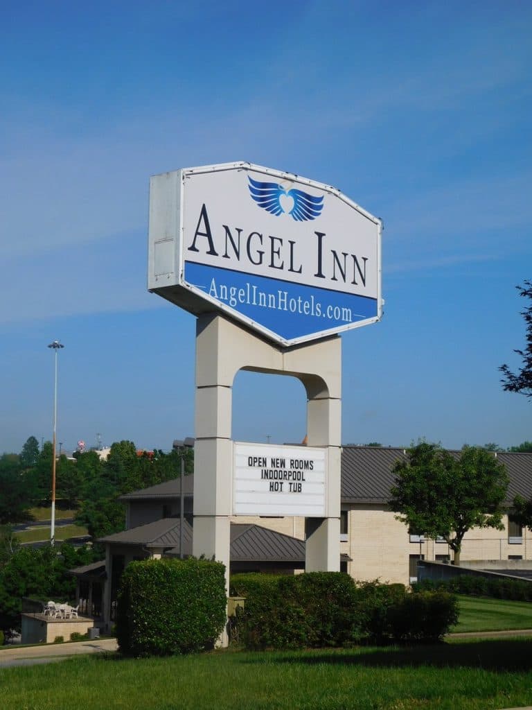 Exterior view of the Angel Inn hotel sign at Angel Inn Central in Branson, Missouri, with the property buildings and landscaped grounds in the background