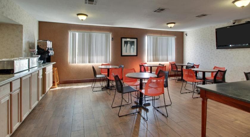 Breakfast area at Angel Inn Central in Branson MO with buffet counter, café tables, chairs, and wall mounted TV