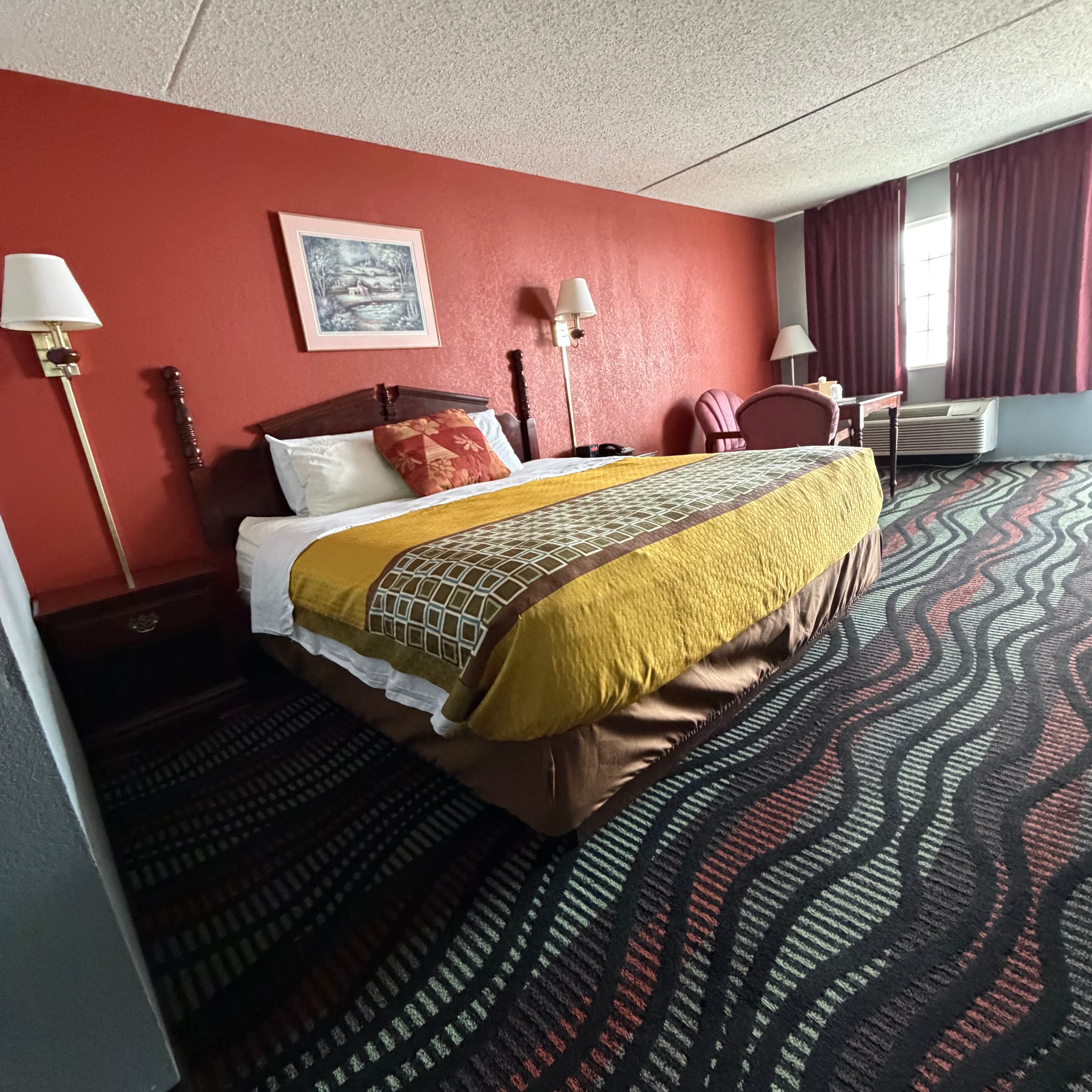 Renovated king guest room at Angel Inn Central with a king bed, wall lamps, and seating area
