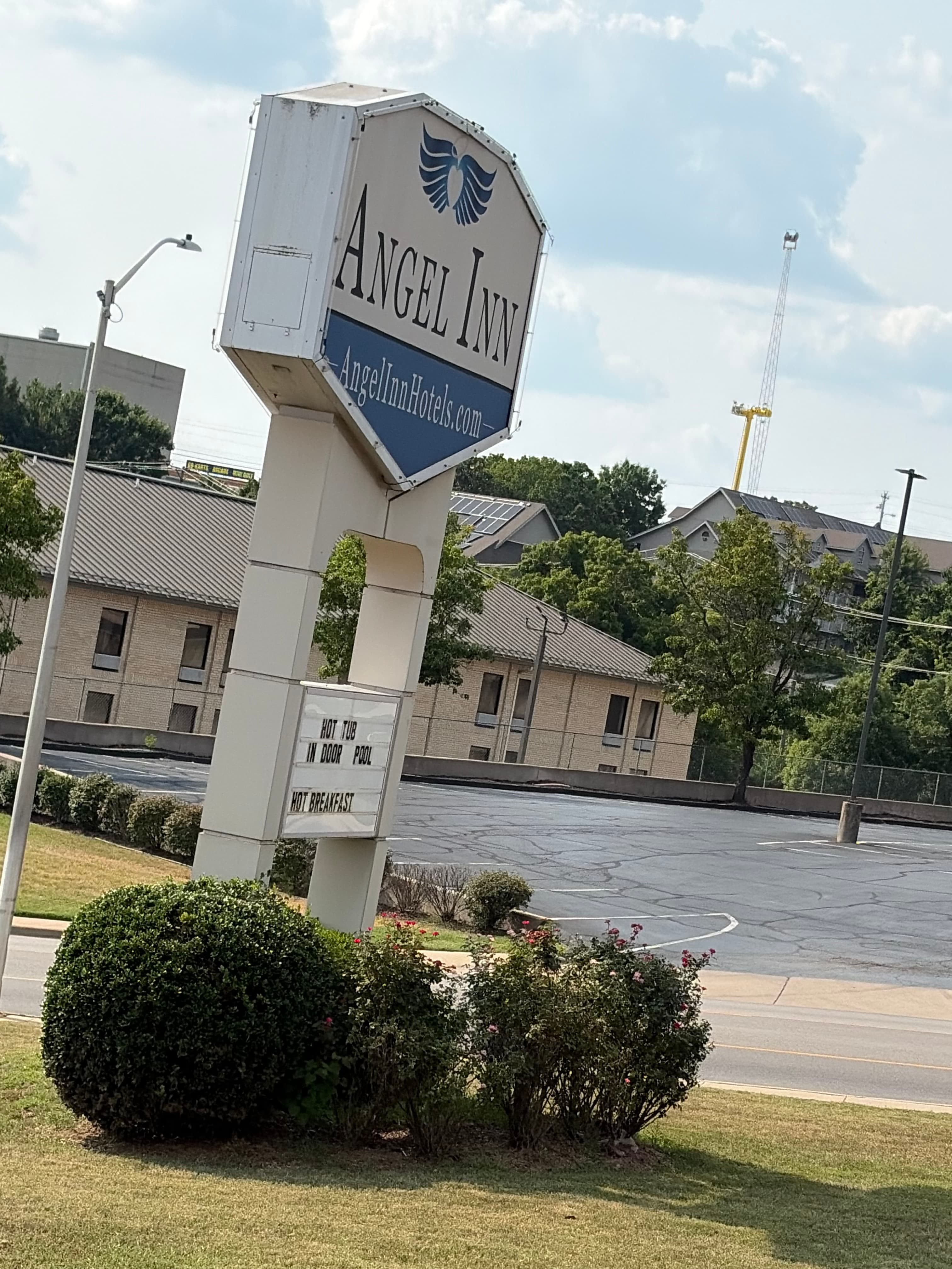 Exterior view of Angel Inn Central in Branson with the hotel sign, parking lot, and guest building